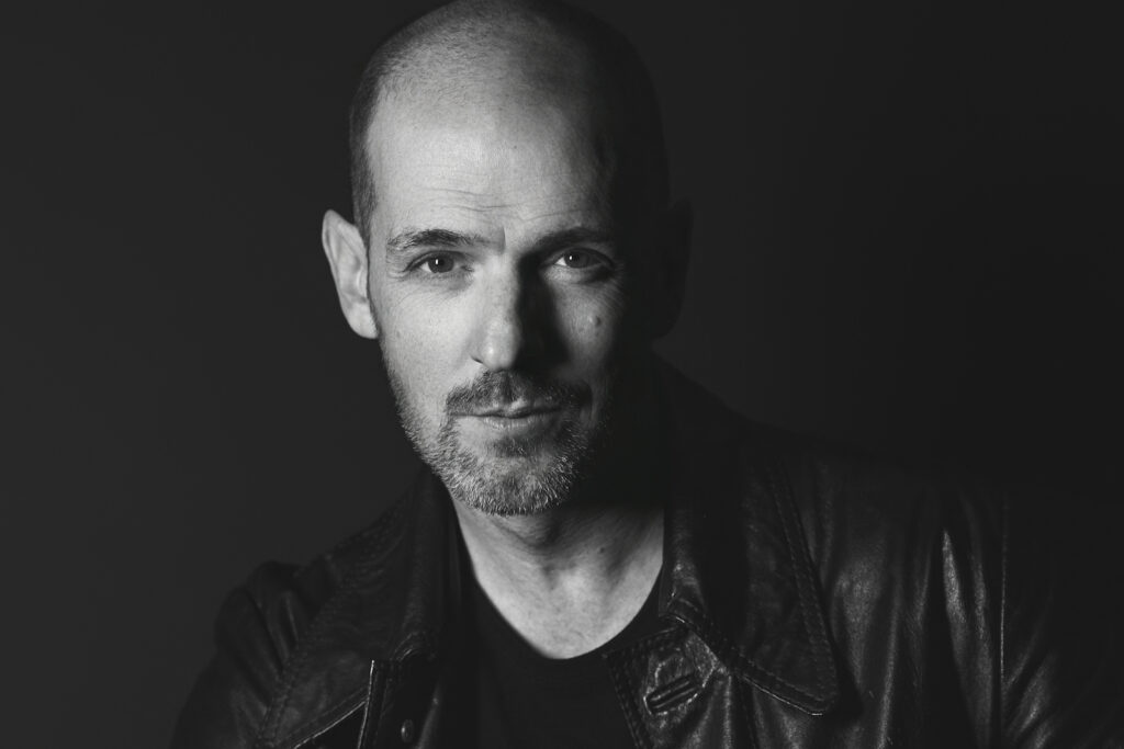 Black and white portrait of John wearing a leather coat