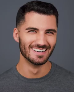 Aaron smiling in a gray crewneck shirt against a gray background.