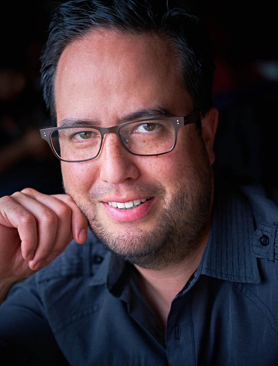 Man wearing glasses photographed in a relaxed environmental portrait.