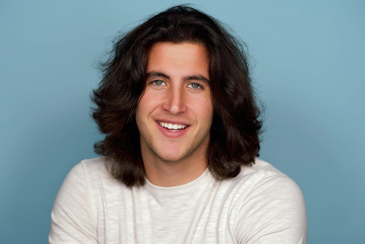 Bennett smiling in a white shirt against a muted blue background