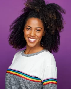Smiling woman with natural curls photographed against a purple studio background in a colorful creative portrait.