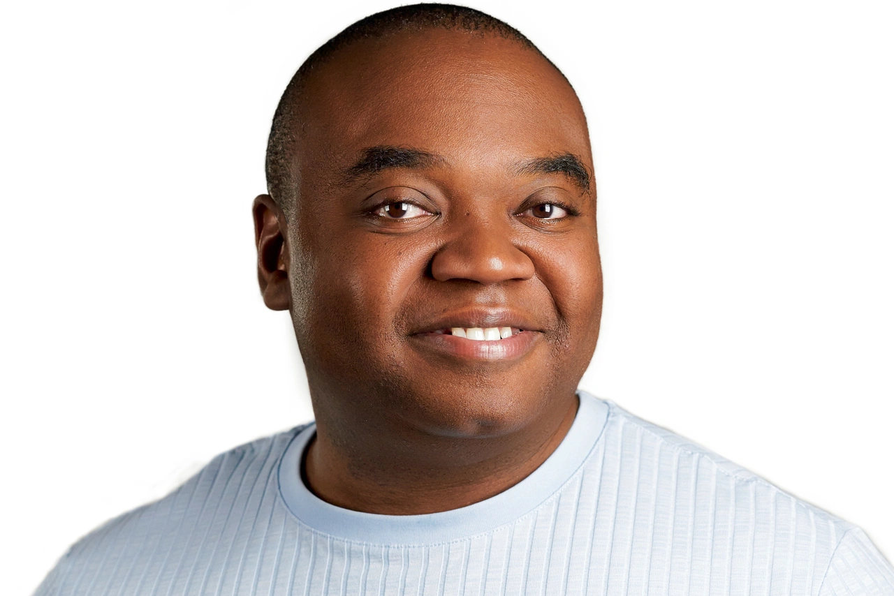 Henry smiling in a pale blue ribbed shirt against a white background.