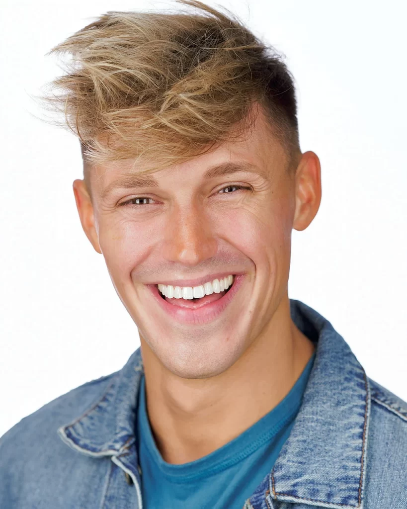 Joe Royal smiling in a denim jacket and blue shirt against a white background