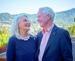 Apollo 9 astronaut Rusty Schweickart and Nancy Ramsey smiling together in an outdoor portrait.
