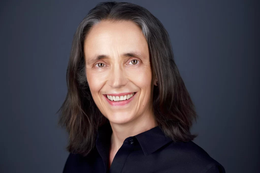 Therapist Judith Nitchie smiling in a black collared shirt against a gray background