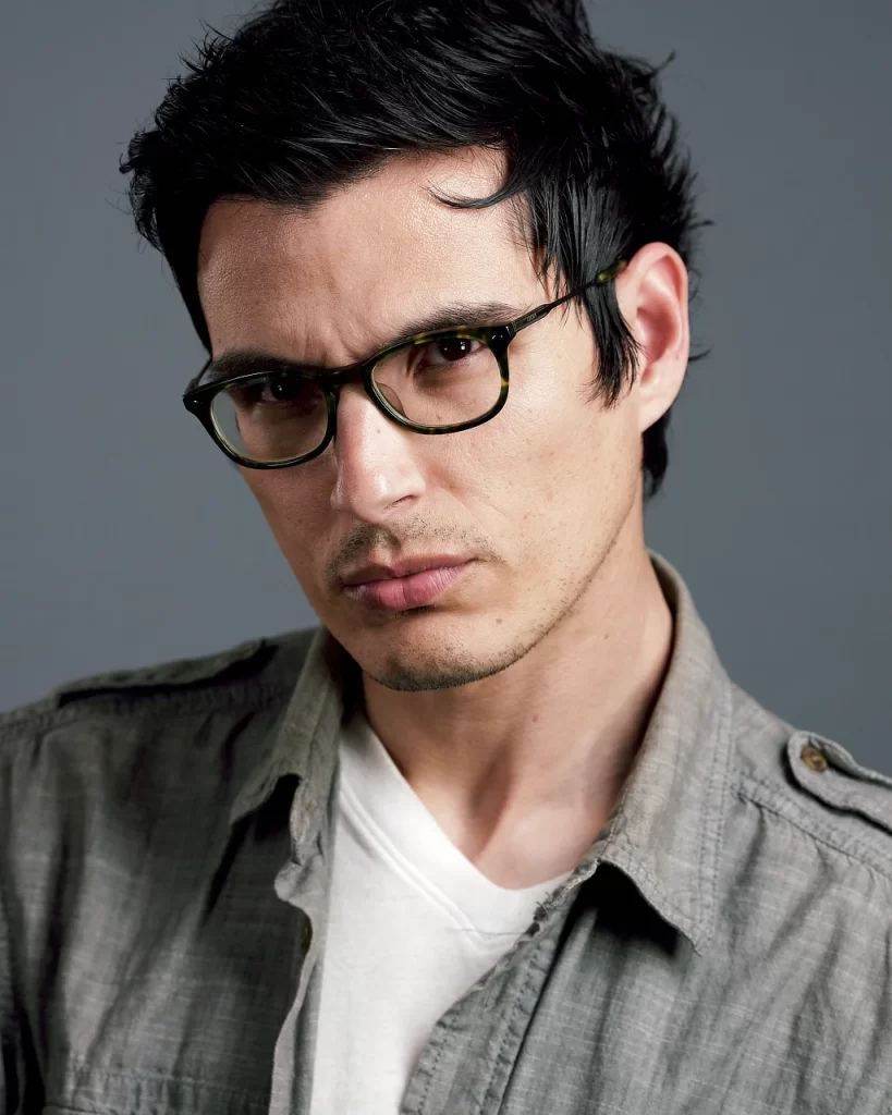 Male modeling headshot of Victor wearing glasses against a gray studio background.